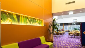 A reception area with a purple and yellow sofa, a large potted plant, and a patterned carpet.