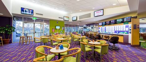A hotel lobby with multiple seating areas, a reception desk, and digital screens displaying information.