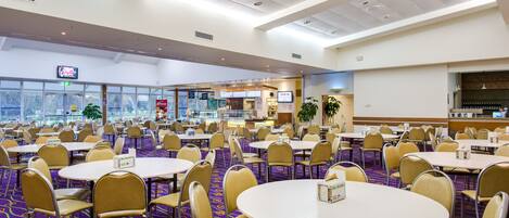 A conference room with round tables and chairs, a buffet area, and a television screen.