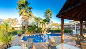 A pool area with lounge chairs and a covered seating area.
