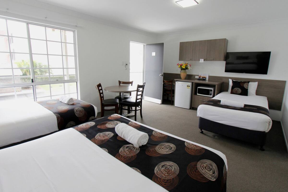 Habitación de hotel con dos camas, un pequeño kitchenette, zona de comedor y televisor.