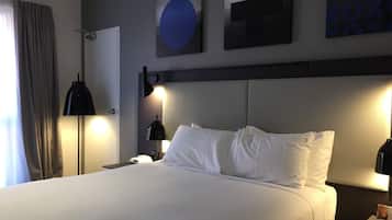 Ein Hotelzimmer mit einem großen Bett, zwei Nachttischlampen, einer Tür und einer Wand mit abstrakter Kunst.