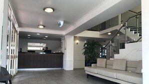 Eine geräumige Lobby mit einer Rezeption, einer Couch und einer Treppe.