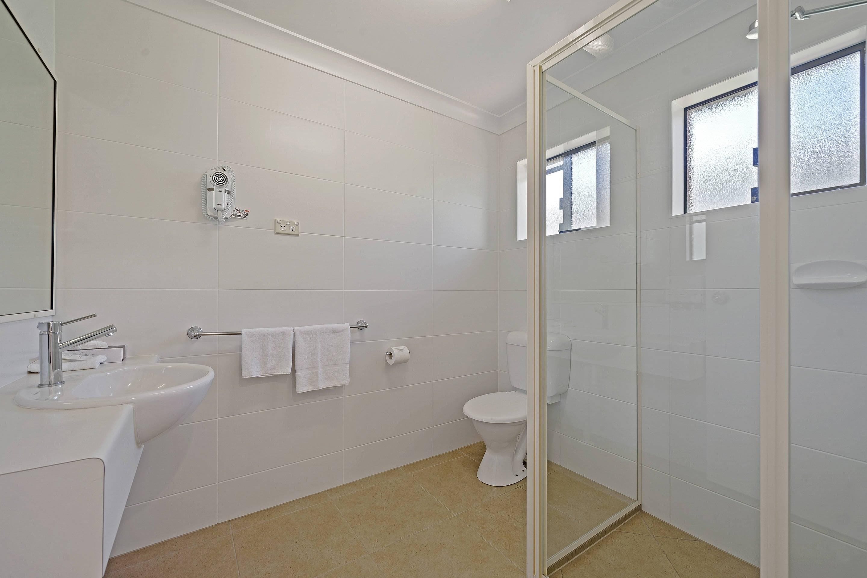 Un baño moderno con lavamanos, inodoro y cabina de ducha de vidrio.
