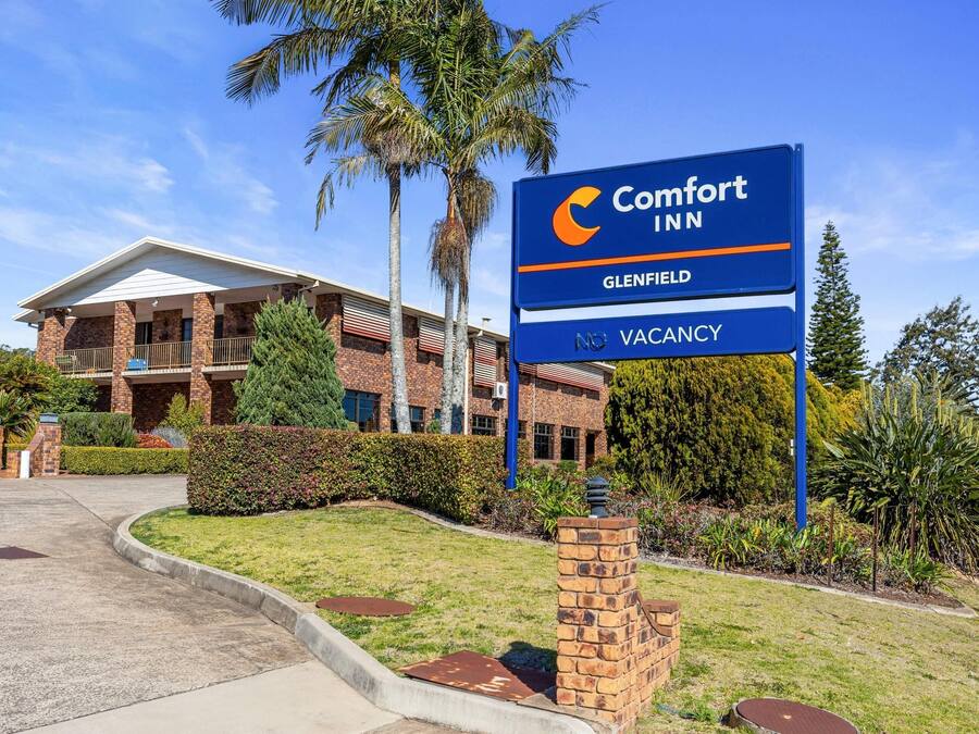 Um hotel Comfort Inn com fachada de tijolos, área externa coberta e placa indicando quartos disponíveis.
