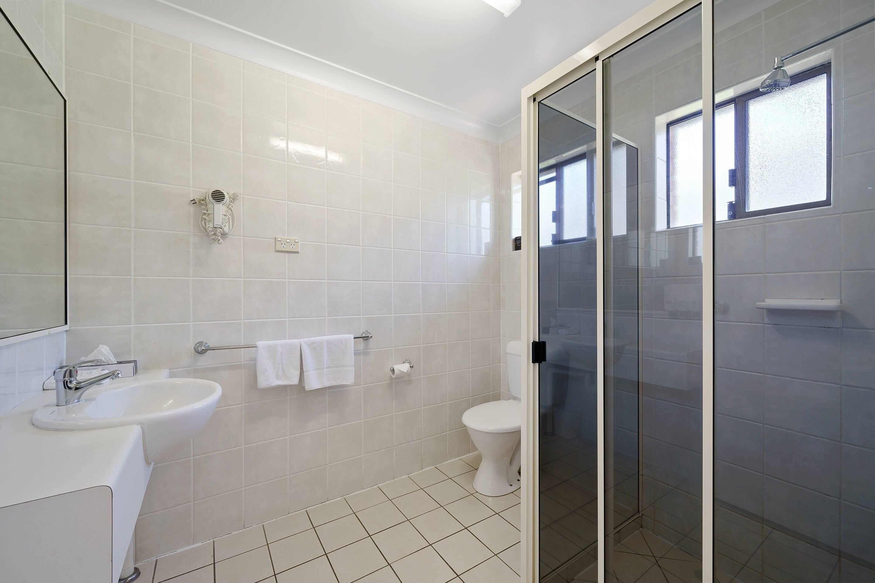A modern bathroom with a glass shower enclosure, a white sink, and a toilet.