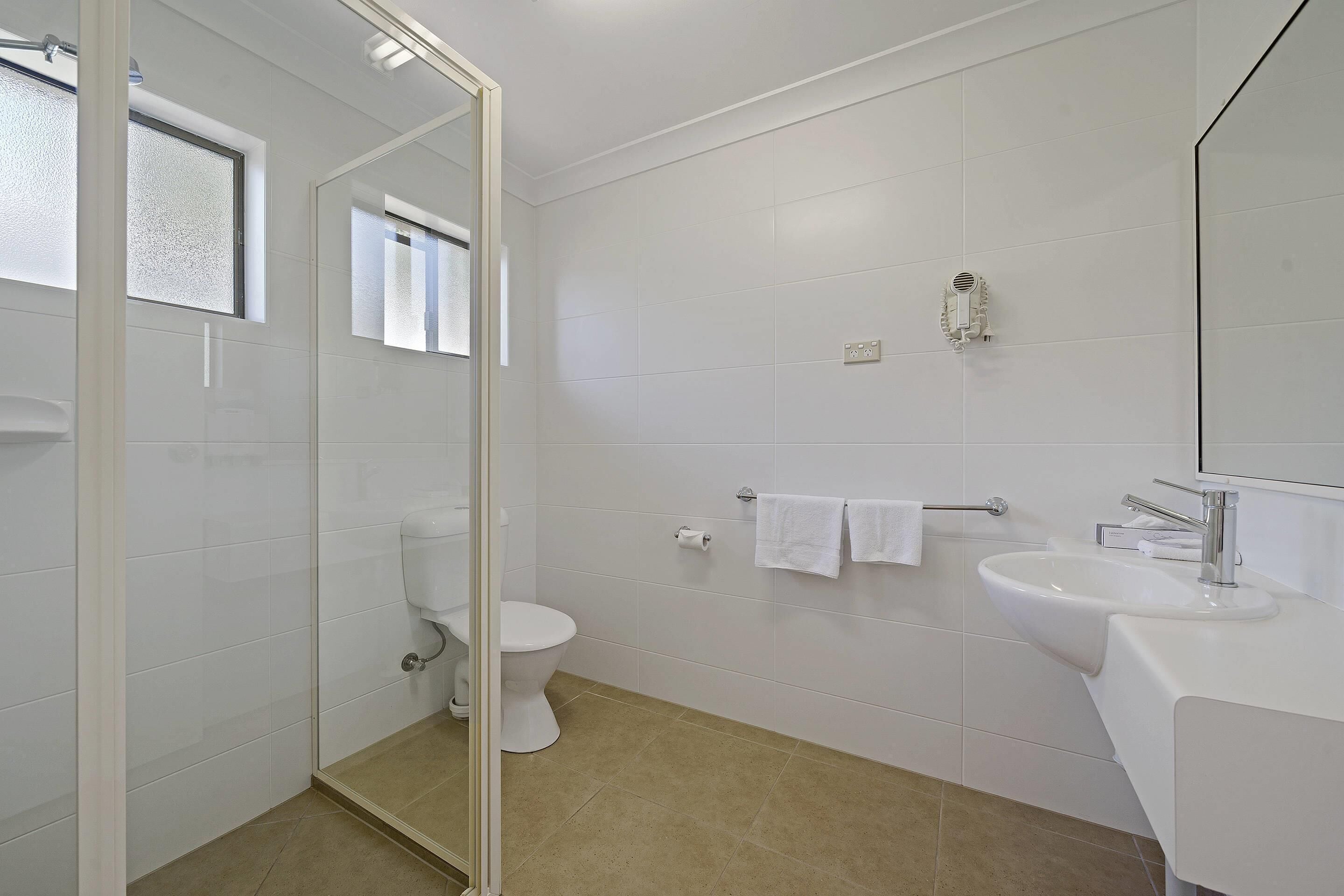 Un baño moderno con inodoro, lavamanos y zona de ducha.