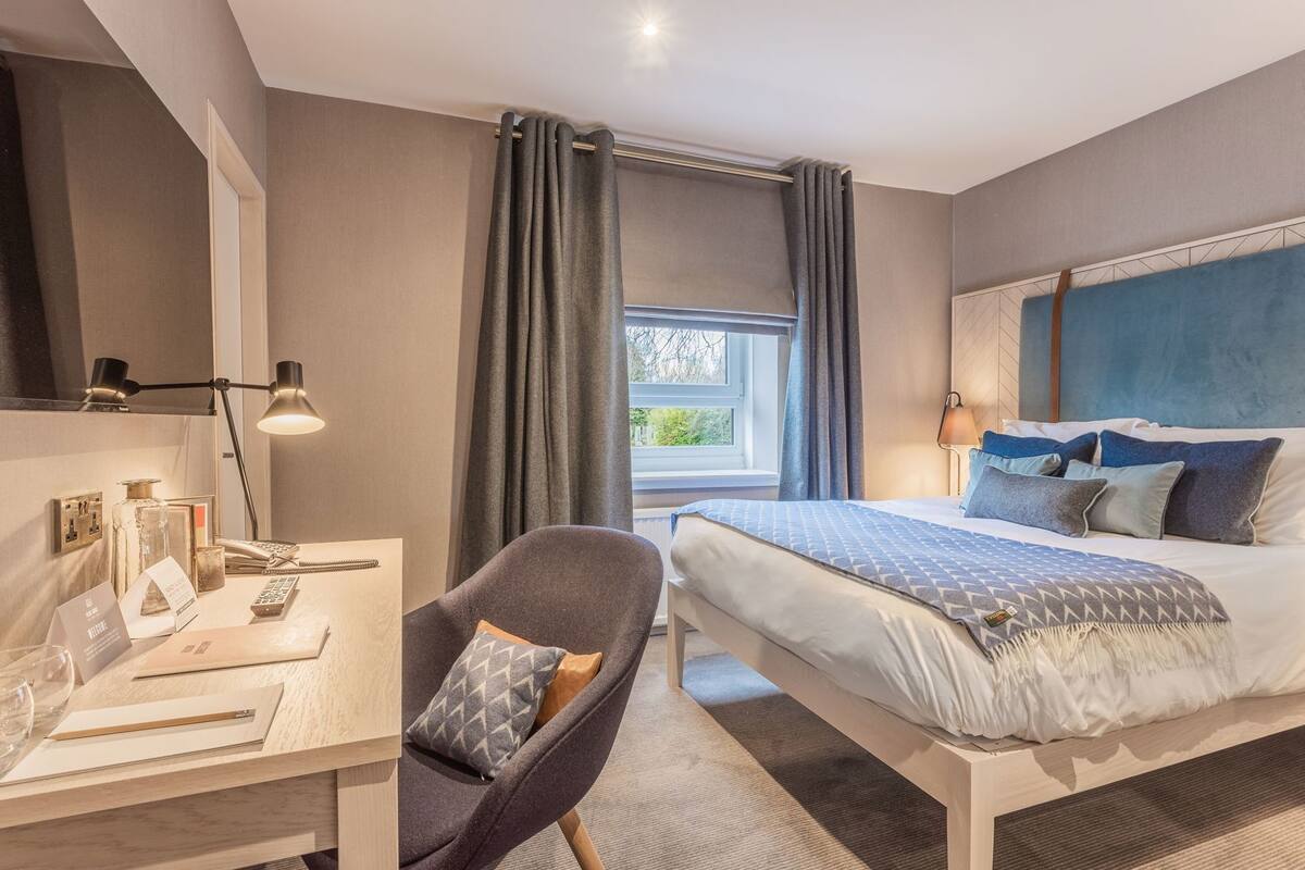 Une chambre d’hôtel moderne équipée d’un lit, d’un bureau, d’une chaise et offrant une vue sur l’extérieur.