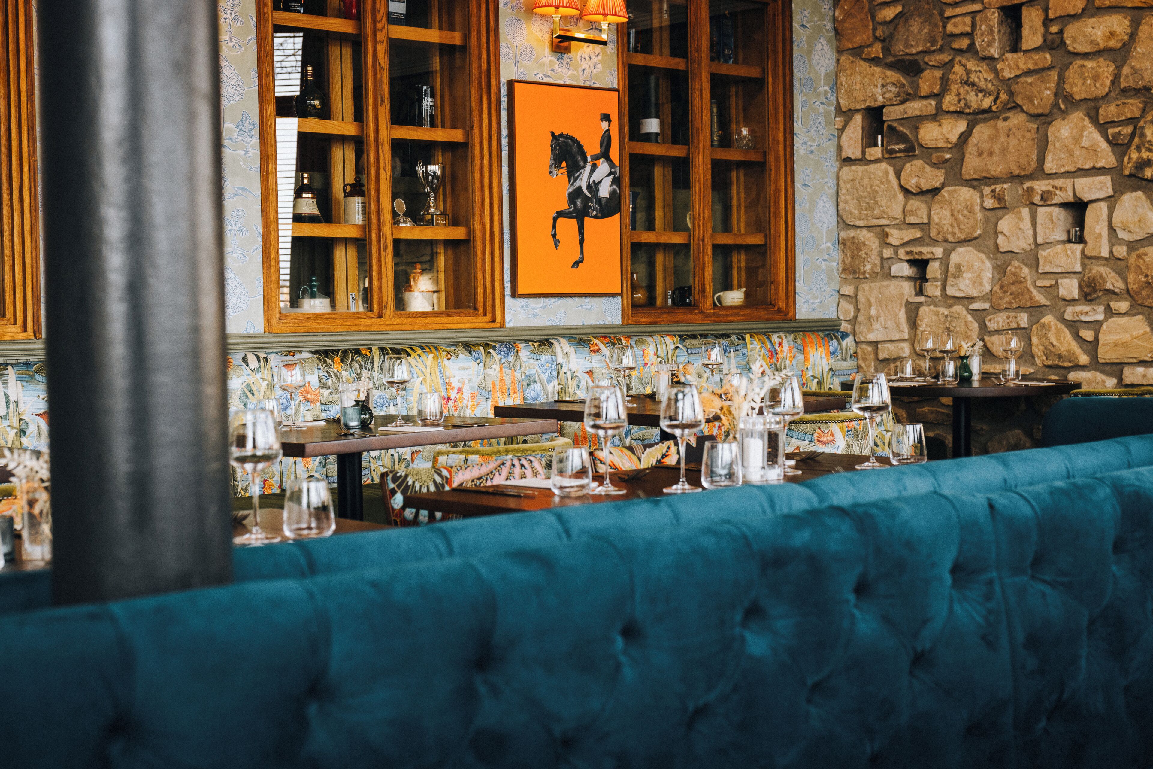 A restaurant interior with a stone wall, wooden cabinets, and a blue upholstered bench.