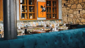 Een restaurantinterieur met een stenen muur, houten kasten en een blauwe gestoffeerde bank.