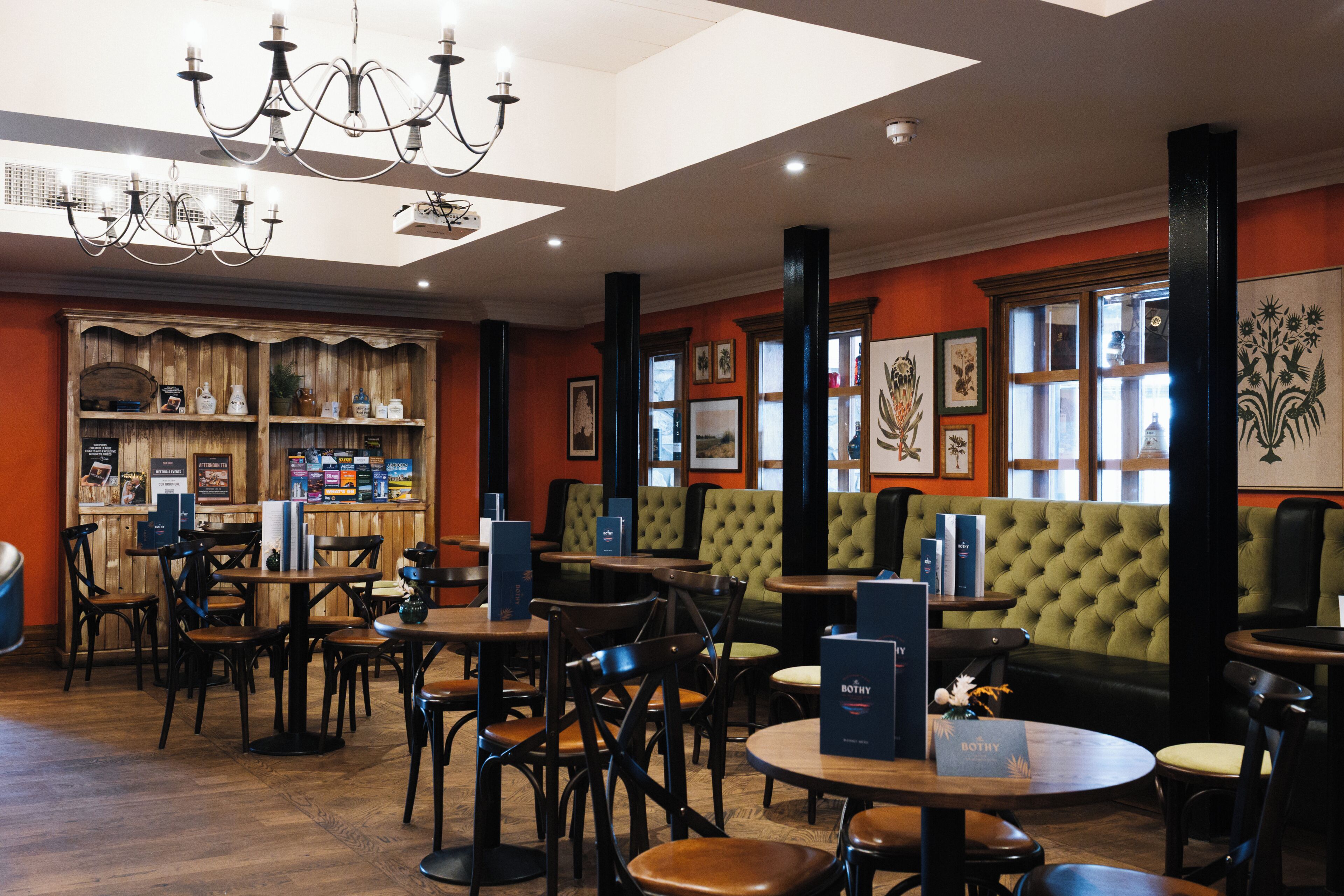 A restaurant with wooden furniture, green upholstered seating, and artwork on the walls.