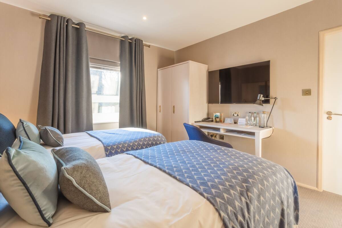 Une chambre d’hôtel avec deux lits, un bureau, une télévision et une armoire.