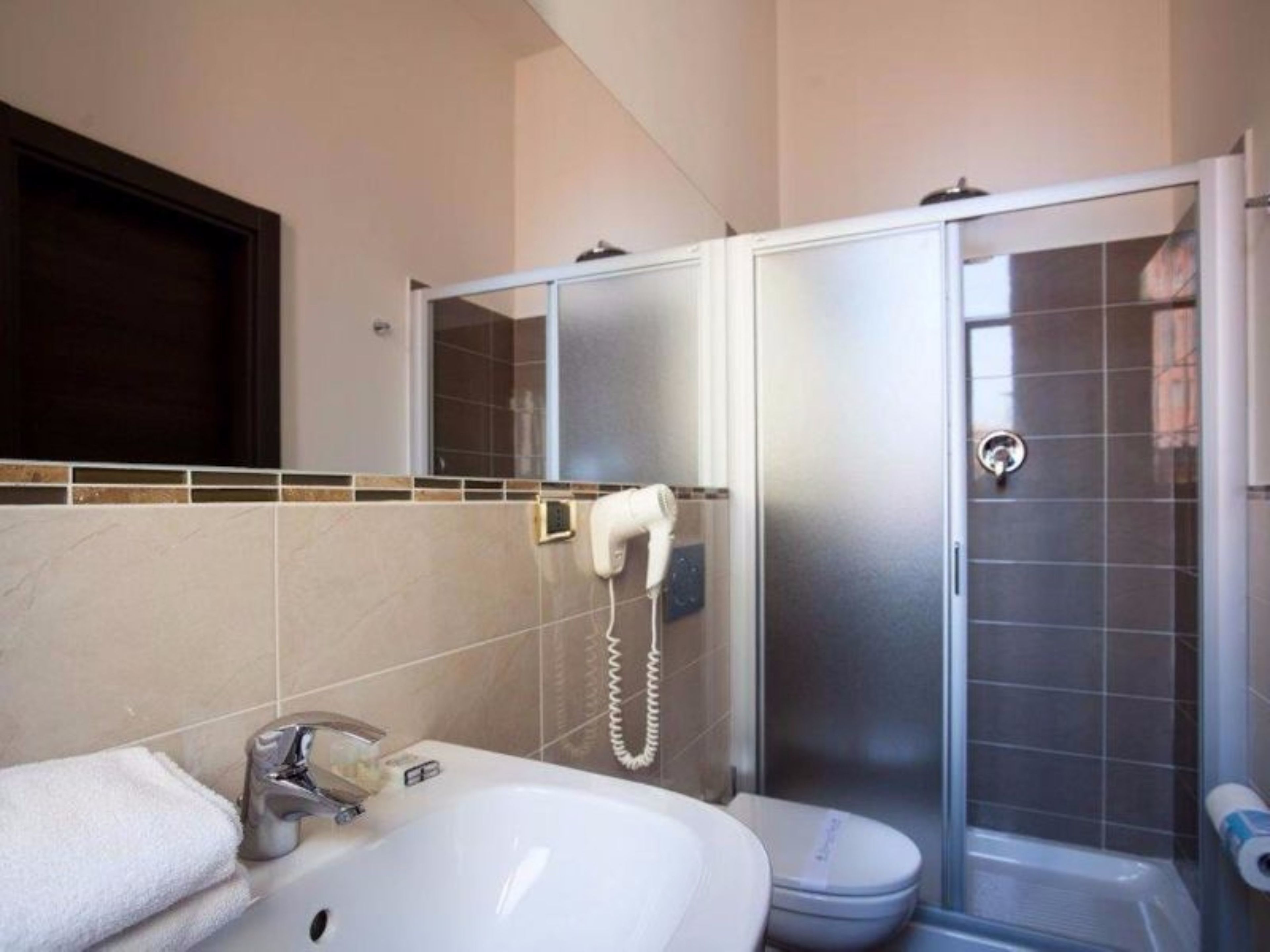 Un baño con lavamanos blanco, inodoro y ducha con cerramiento de vidrio.
