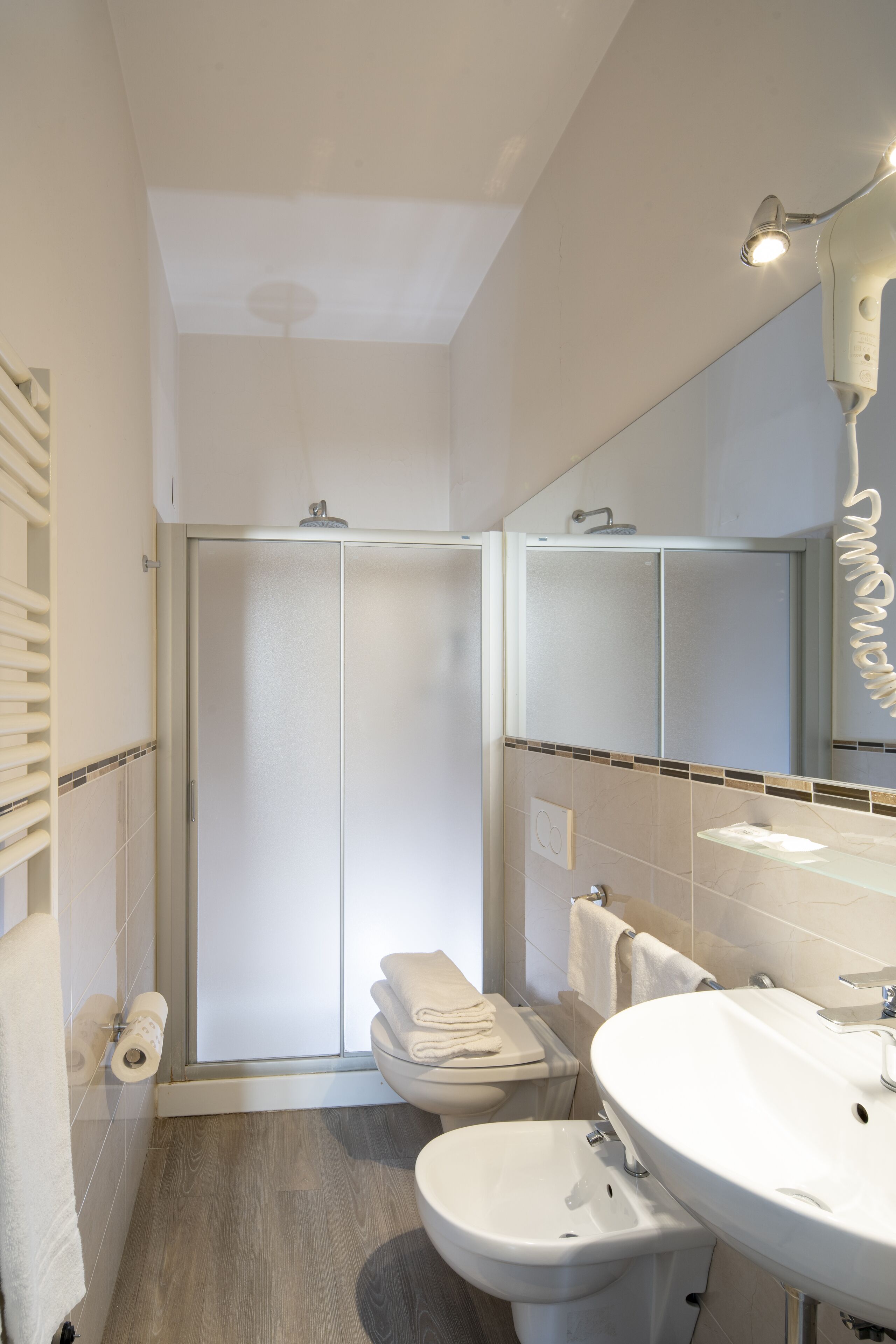 A modern bathroom with a shower, toilet, bidet, and sink.