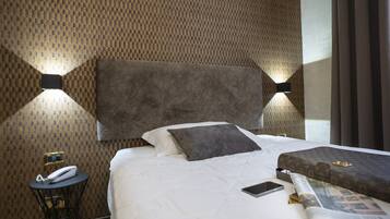 Una camera d'albergo con un letto grande, un comodino con un telefono e una rivista sul letto.