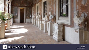Un pasillo de arquitectura clásica, con columnas y bustos a lo largo de las paredes.