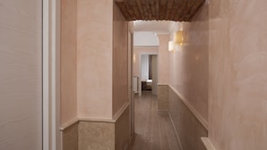 Un pasillo con suelo de baldosas, un arco de ladrillo e iluminación en la pared.