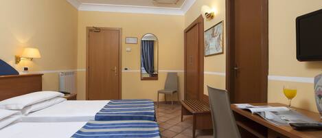 A hotel room with two beds, a desk, a chair, a TV, and a window with curtains.