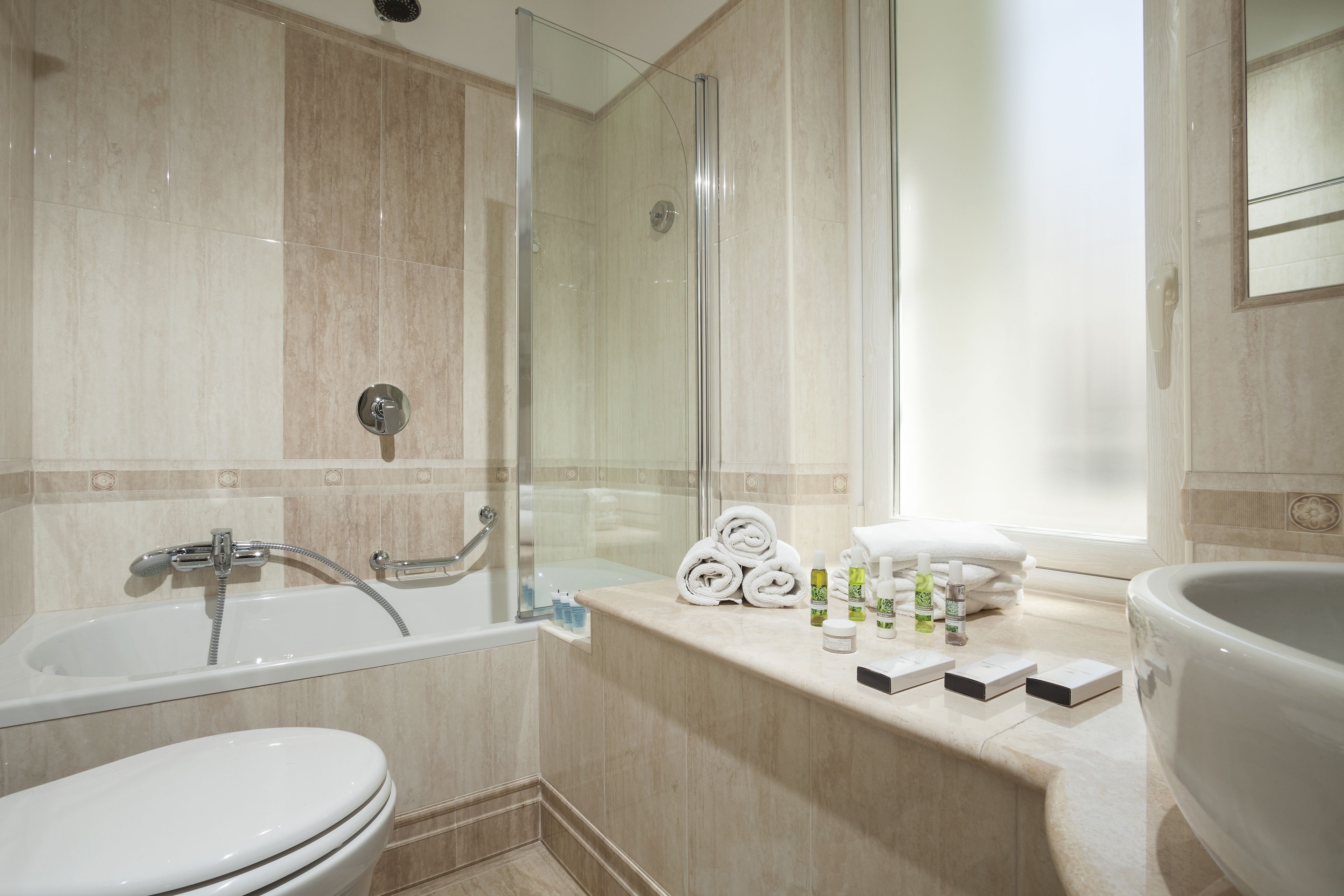 Een moderne badkamer met een bad, toilet en douche.