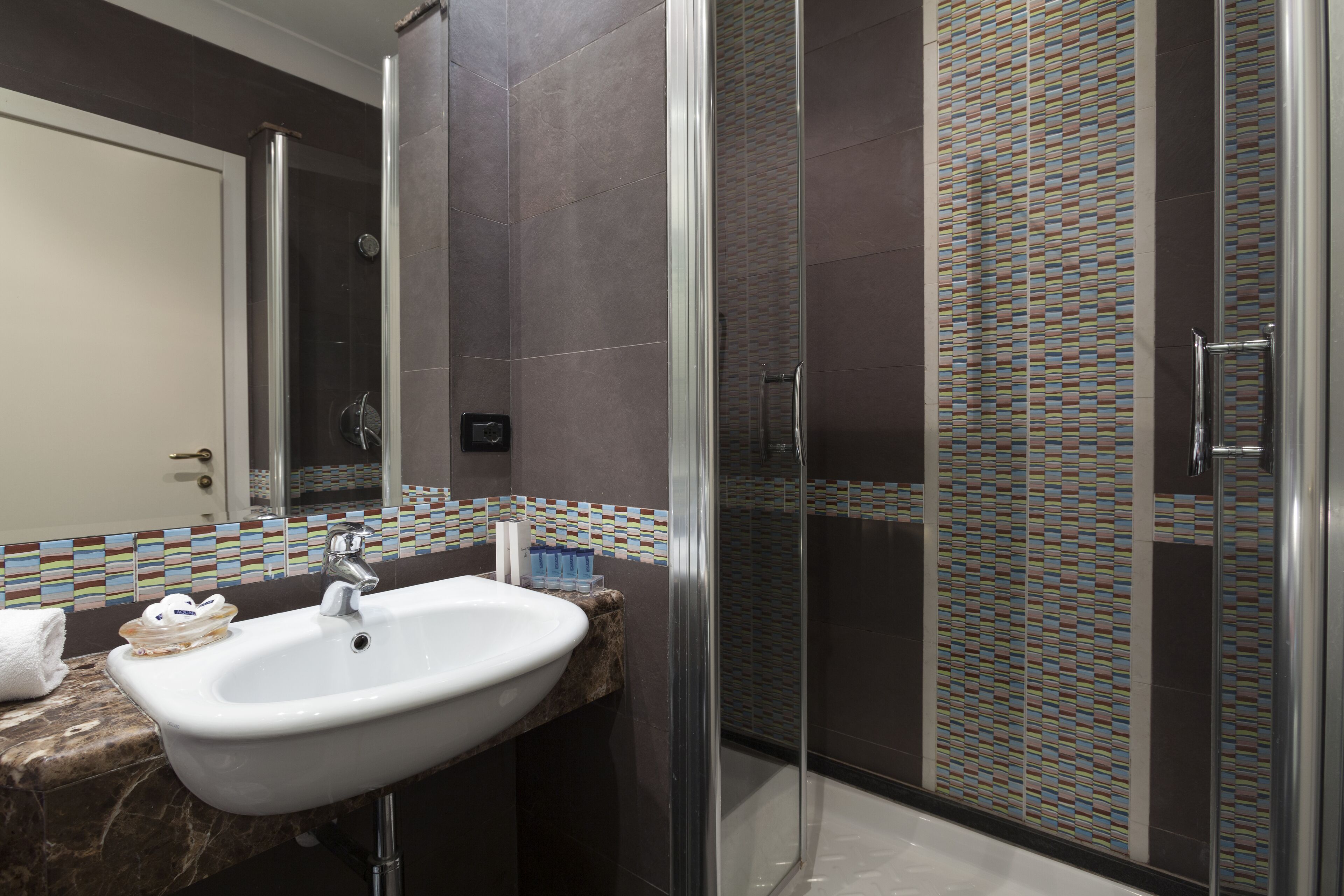 A modern bathroom with a glass-enclosed shower, a white sink, and a tiled backsplash.
