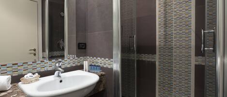 A modern bathroom with a glass-enclosed shower, a white sink, and a tiled backsplash.