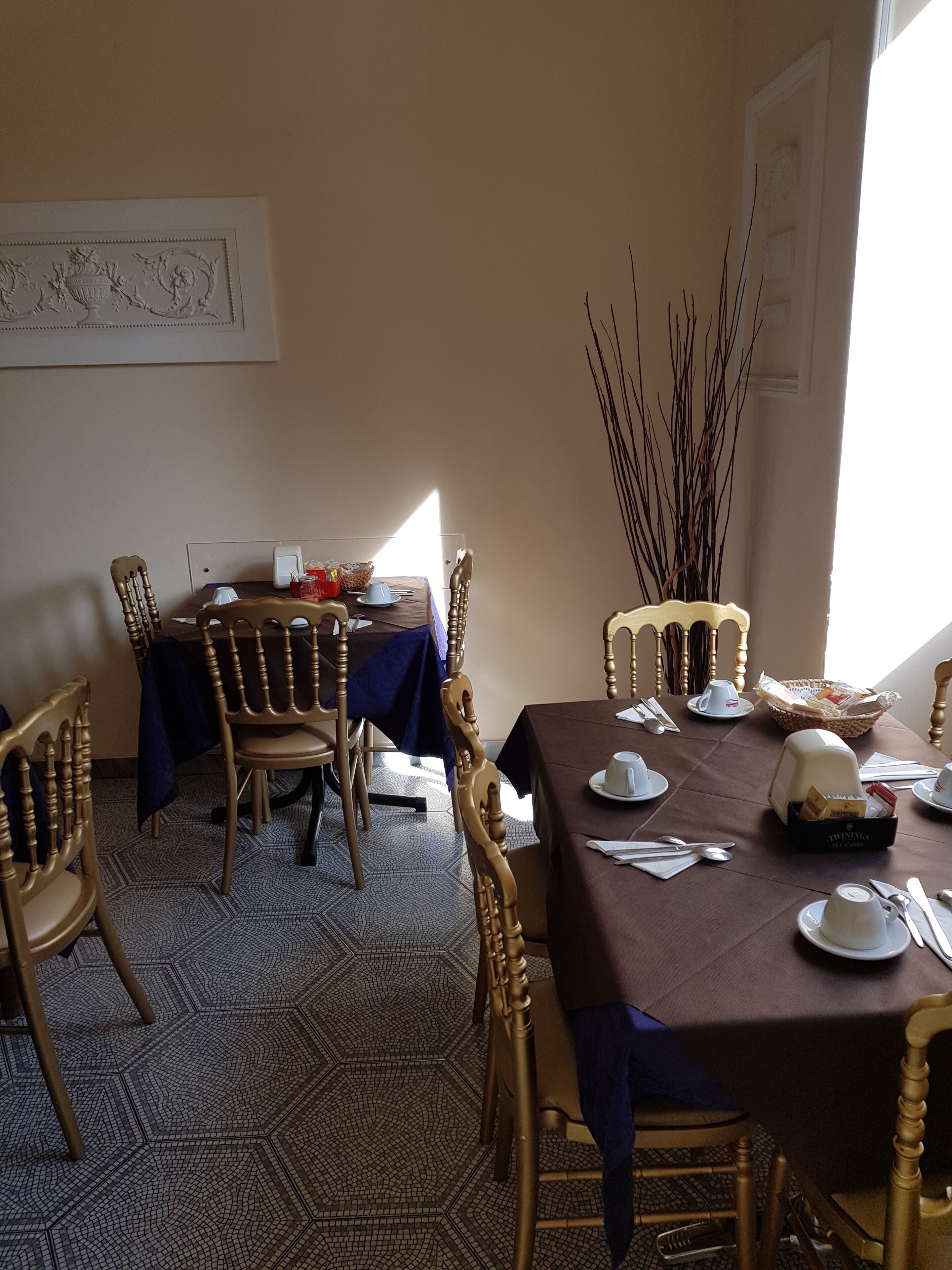 A dining area with a table set for four, surrounded by wooden chairs with intricate carvings.