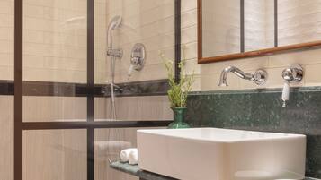 Un baño moderno con cabina de ducha de vidrio, un espejo grande y encimera de mármol.