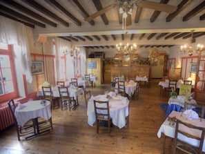 Un restaurant amb bigues de fusta, teles de taula blanques i lluminàries penjants.