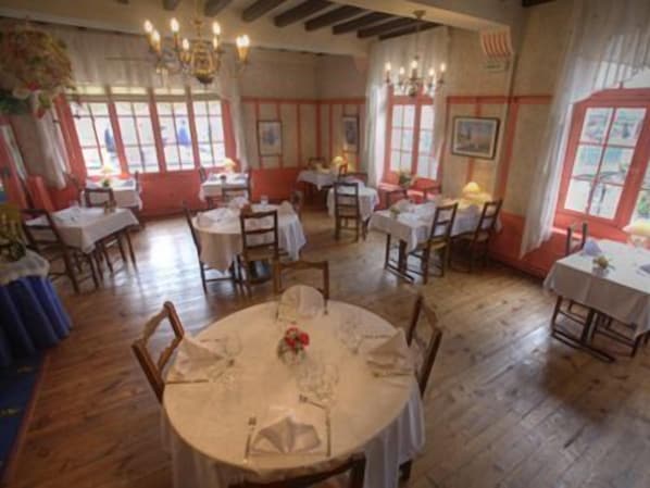Un espace repas avec des tables rondes, des chaises et des lustres.