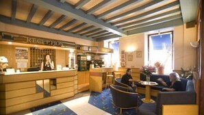 A reception area with a wooden counter, a bar, and seating for guests.