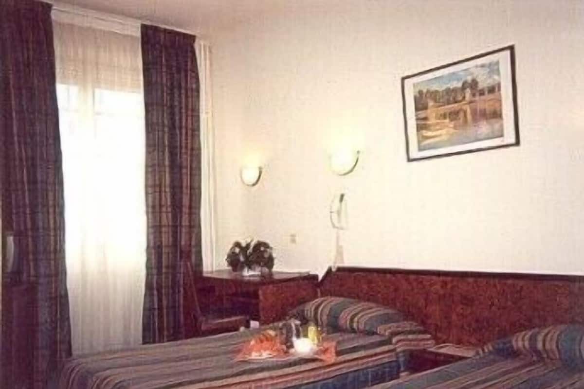 A hotel room with a bed, a bedside table, a lamp, and a painting on the wall.