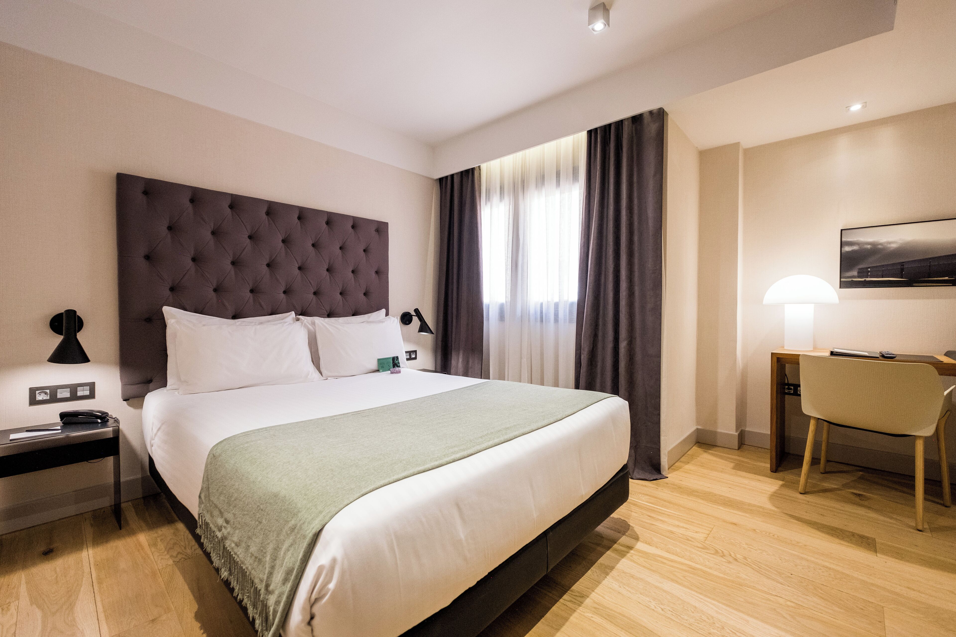 A hotel room with a large bed, a desk, and a chair.