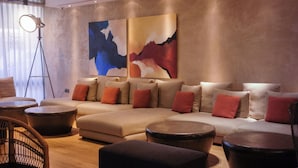 Un salon moderne avec un canapé d’angle, des poufs ronds et un lampadaire.