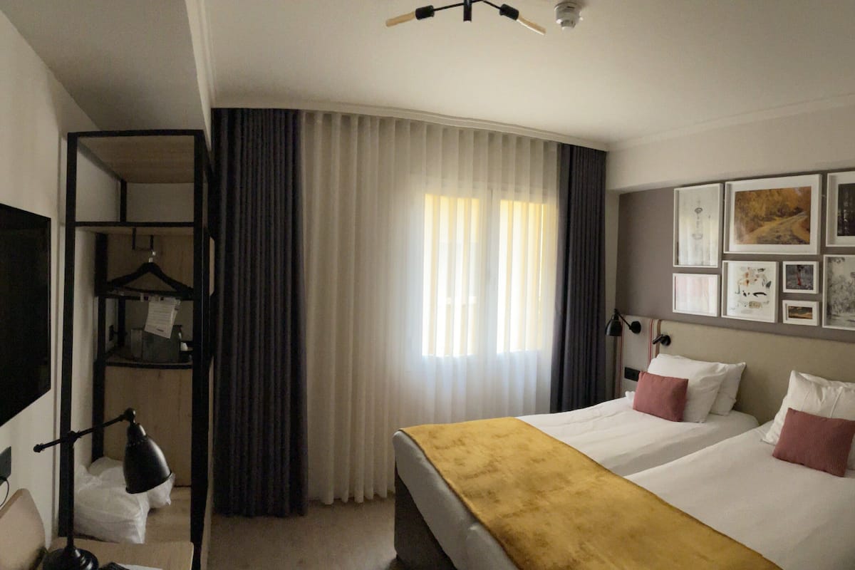 A hotel room with a bed, a TV, a desk, and a wardrobe.