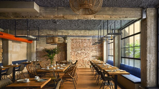 Un restaurante con paredes de ladrillo, mesas de madera y luminarias modernas.