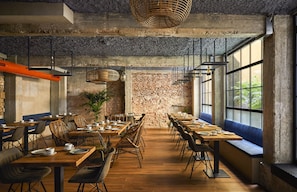 Un restaurante con paredes de ladrillo, mesas de madera y luminarias modernas.