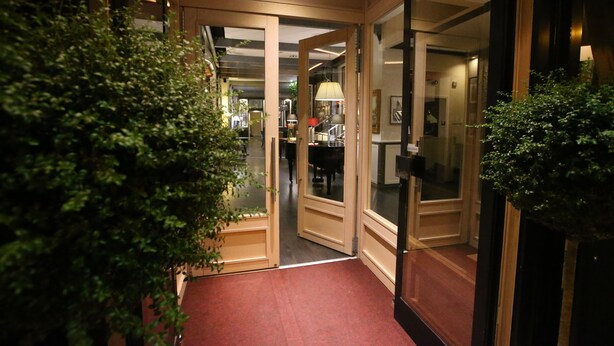 A hotel corridor with glass doors leading to a room, a red carpet, and a potted plant. - Hotel Italia (Verona)