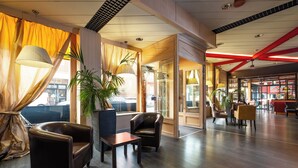 A spacious lobby with leather armchairs, a coffee table, and potted plants. - Hotel Italia (Verona)