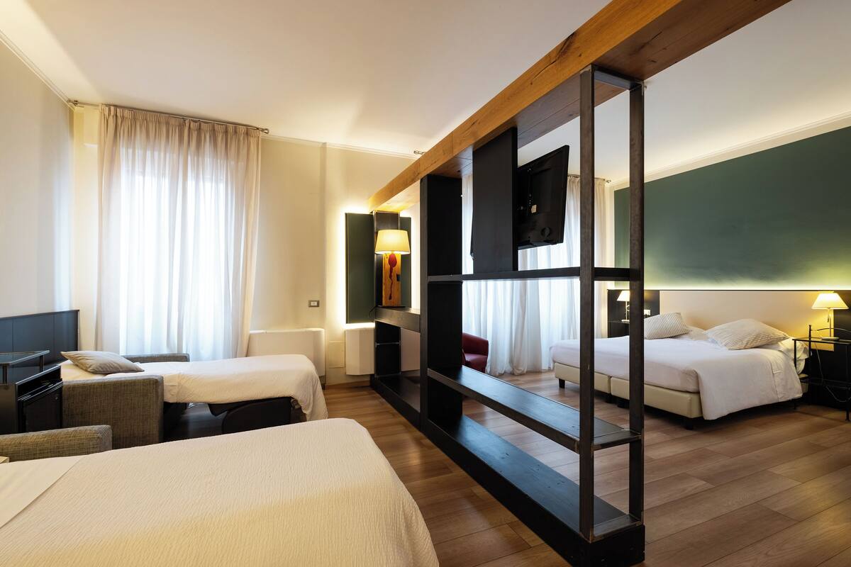 Ein Hotelzimmer mit zwei Betten, einem Schreibtisch, einem Stuhl und einem großen Spiegel.