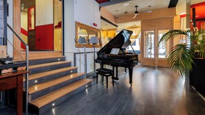 A grand piano in a spacious lobby with a wooden staircase and a large mirror. - Hotel Italia (Verona)