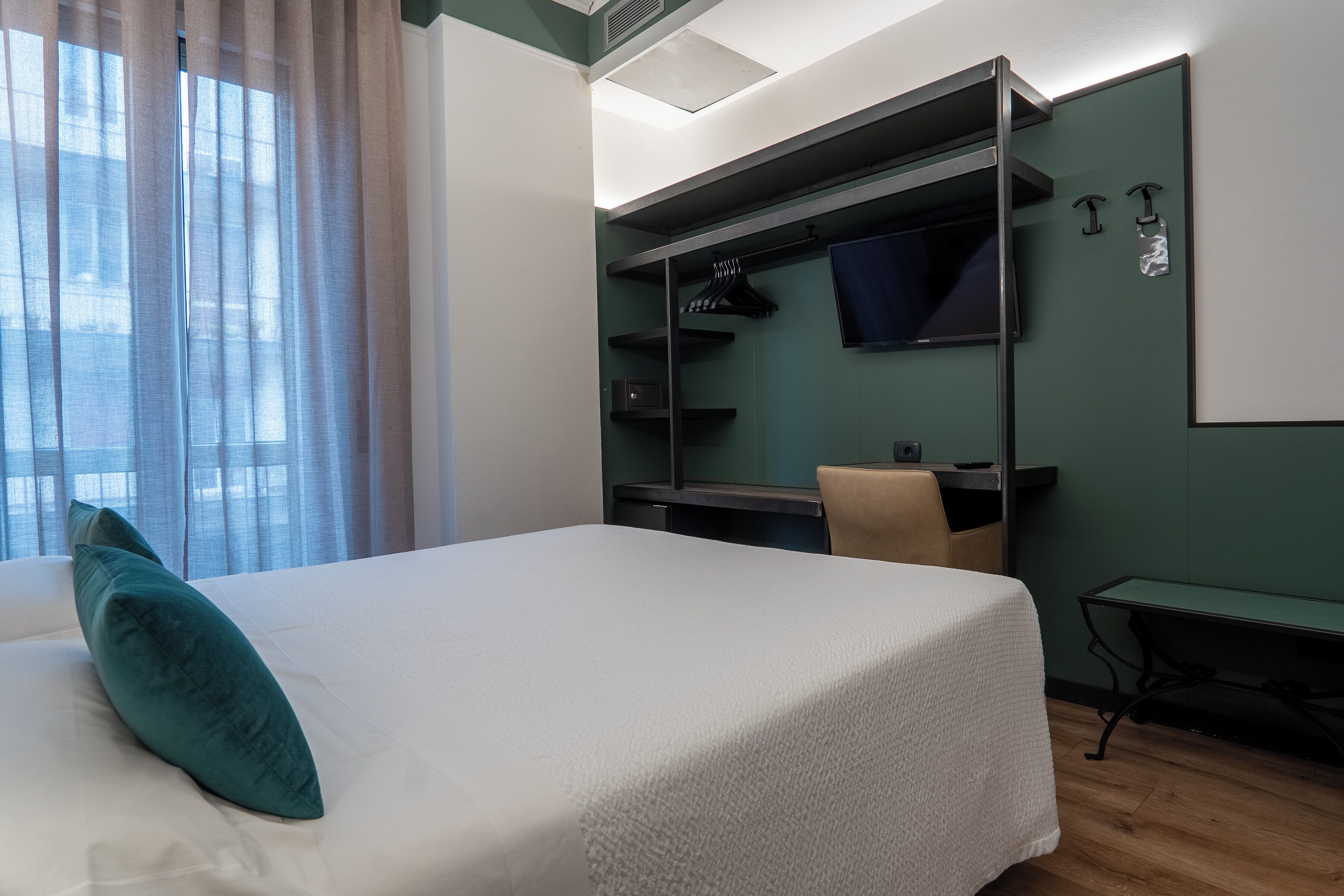 Una camera d'albergo con un letto, una scrivania e un armadio.