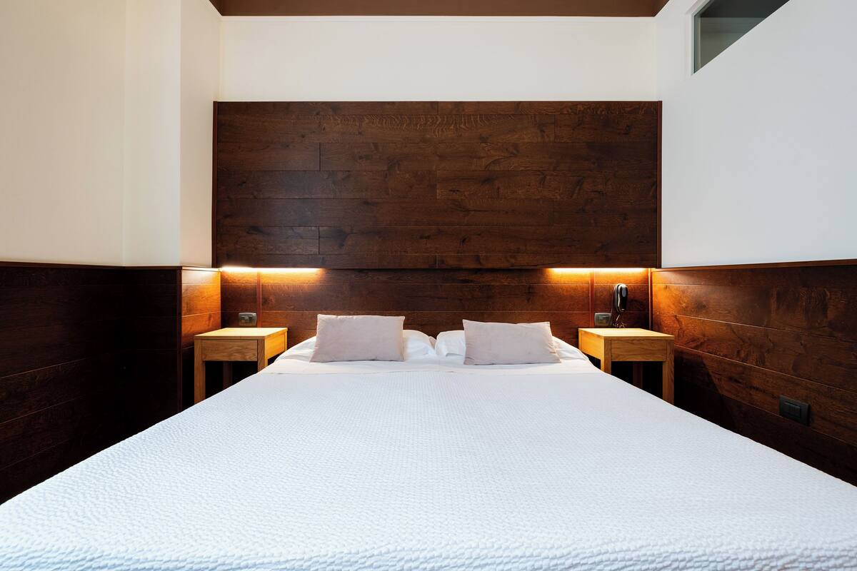 Ein Hotelzimmer mit einem großen Bett, einem Holzkopfende, zwei Nachttischen und einem kleinen Beistelltisch.