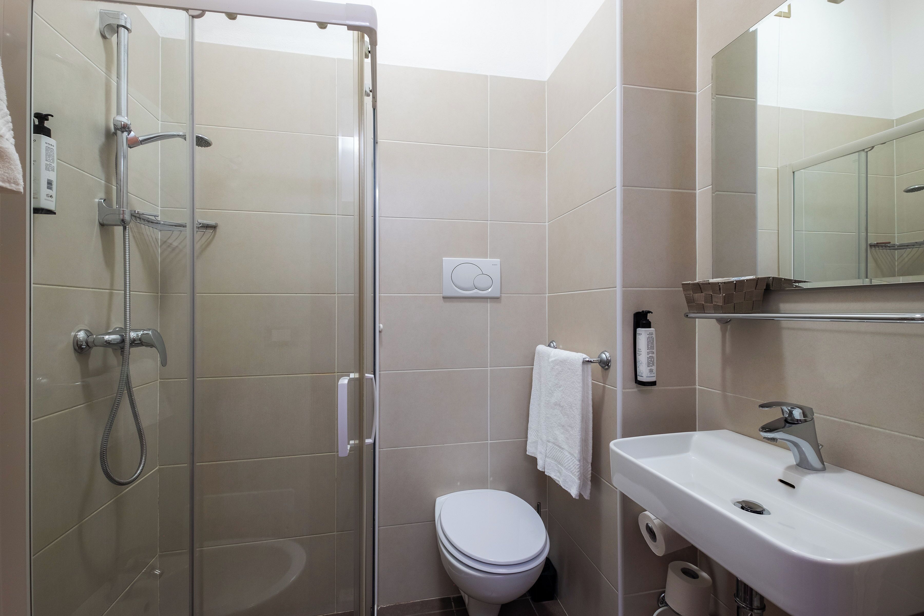 Un bagno moderno con doccia vetrata, un water bianco e un lavandino con specchio sopra.