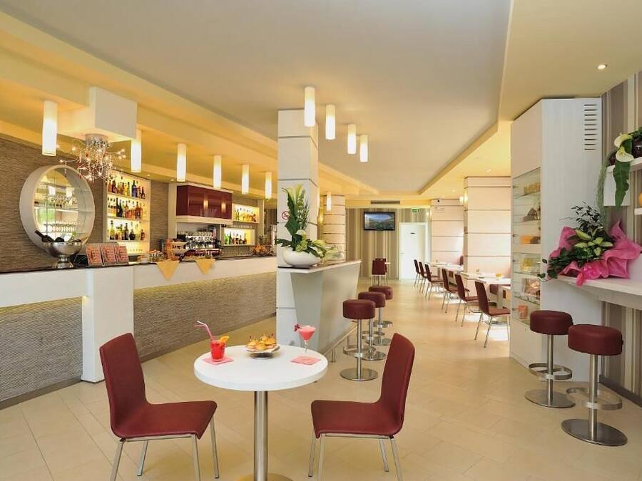 Un moderno vestíbulo de hotel con una zona de bar, asientos y una pantalla de televisión.