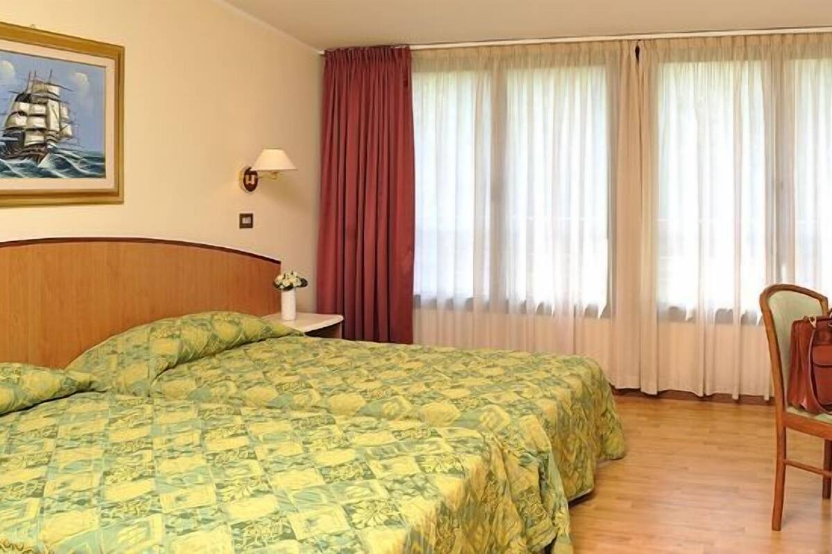 A hotel room with a bed, a desk with a TV, and a chair.