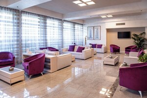 A modern living room with a sofa set, coffee table, and a TV mounted on the wall.