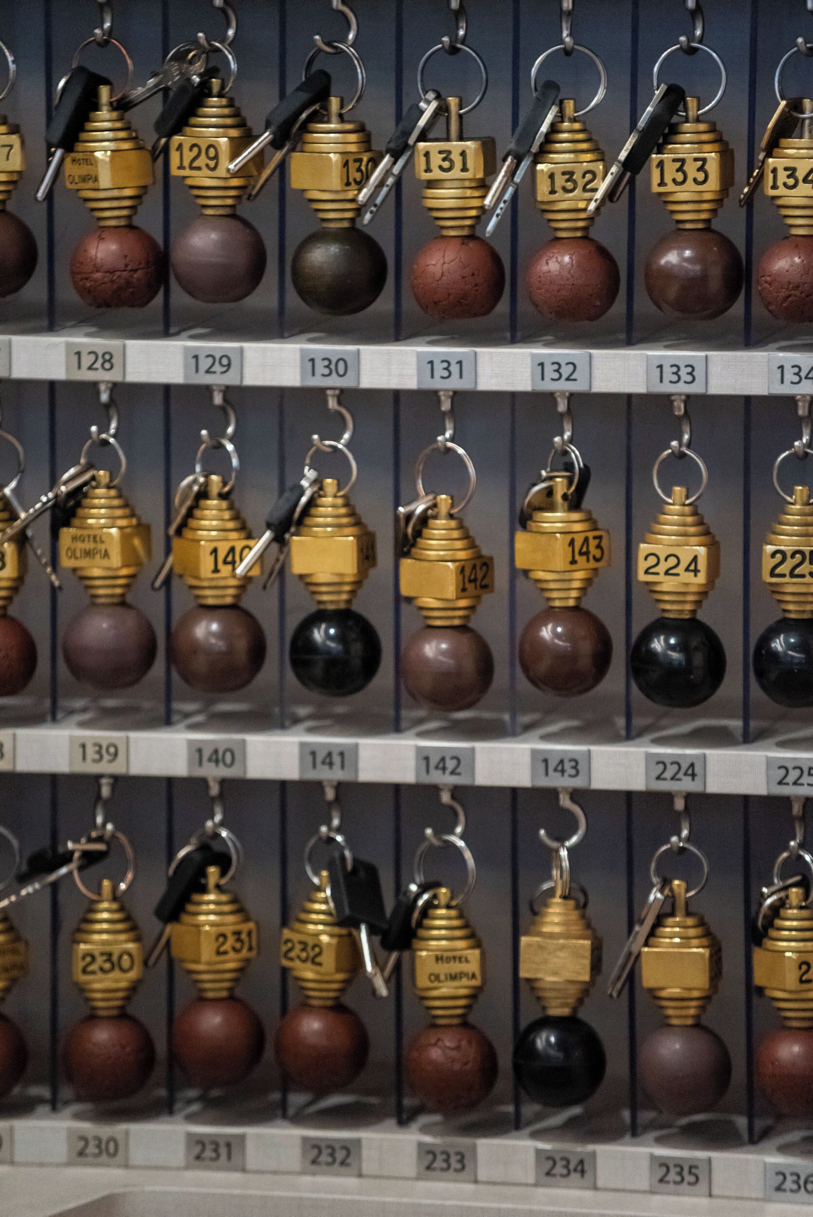 A wall of keychains with numbers and the text "HOTEL OLIMPIA" on them.