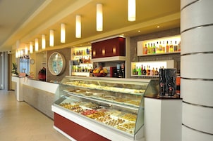 A hotel lobby with a food display, a reception desk, and shelves of liquor bottles.