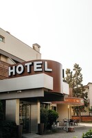 A hotel with a prominent 'HOTEL' sign, outdoor seating area, and a bar named 'OLIMPIO'.