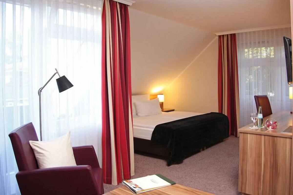 Una habitación de hotel con cama, escritorio, silla y lámpara.